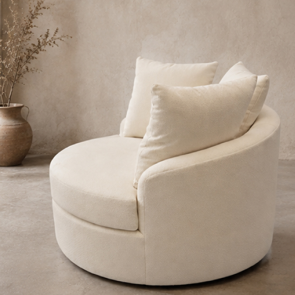 Close-up view of The Royal swivel chair upholstered in cream boucle fabric with two matching pillows